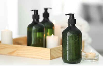 Photo of Wooden tray with soap dispensers and burning candles on white table