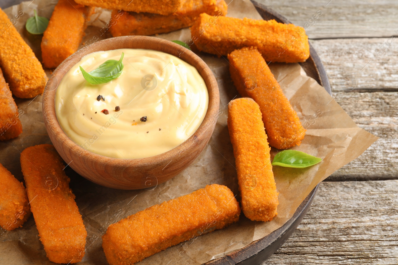Photo of Delicious chicken nuggets and cheese sauce with basil on wooden table, closeup