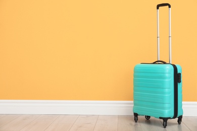 Photo of Suitcase packed for travel on floor near color wall. Space for text