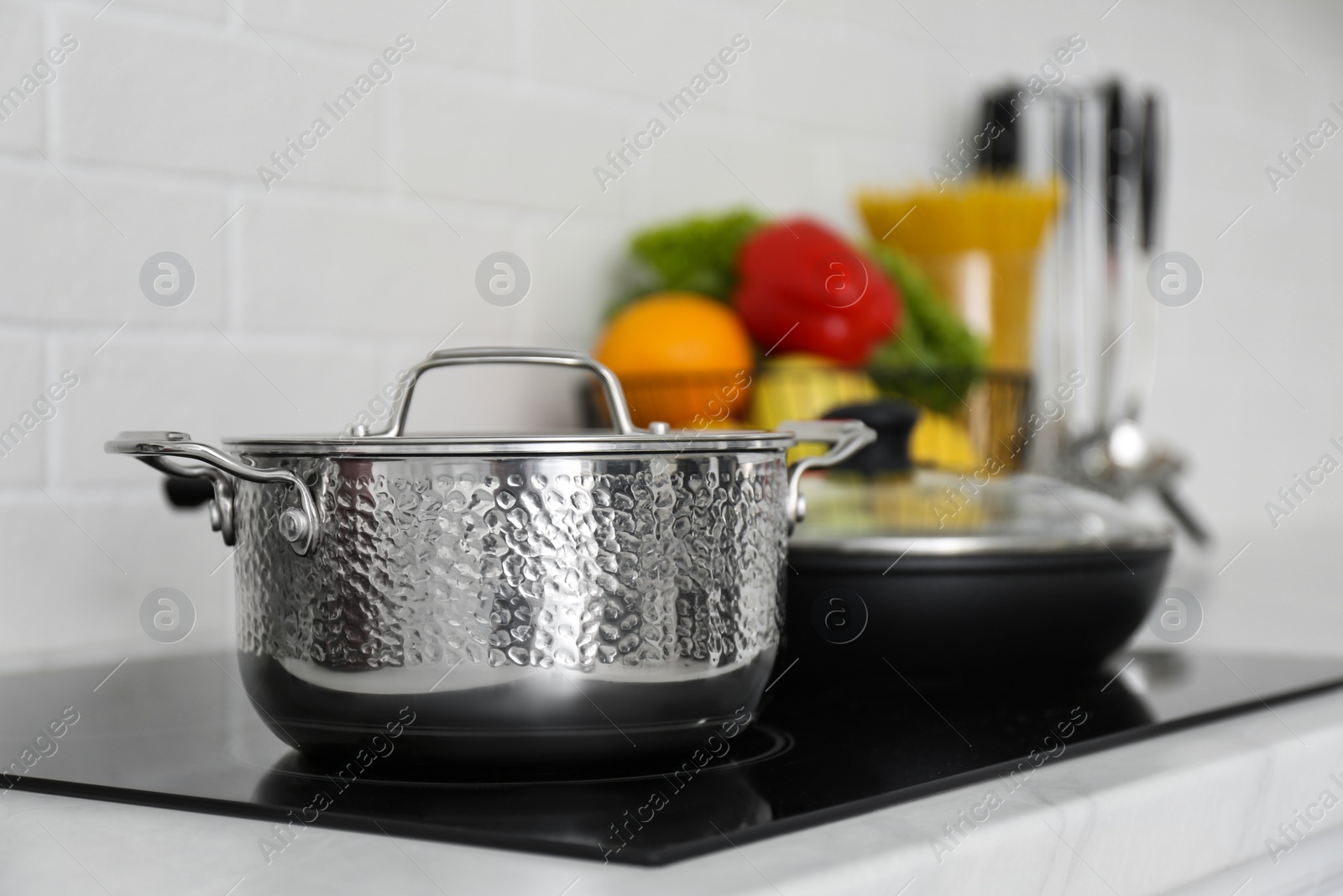 Photo of Saucepot and frying pan on induction stove in kitchen