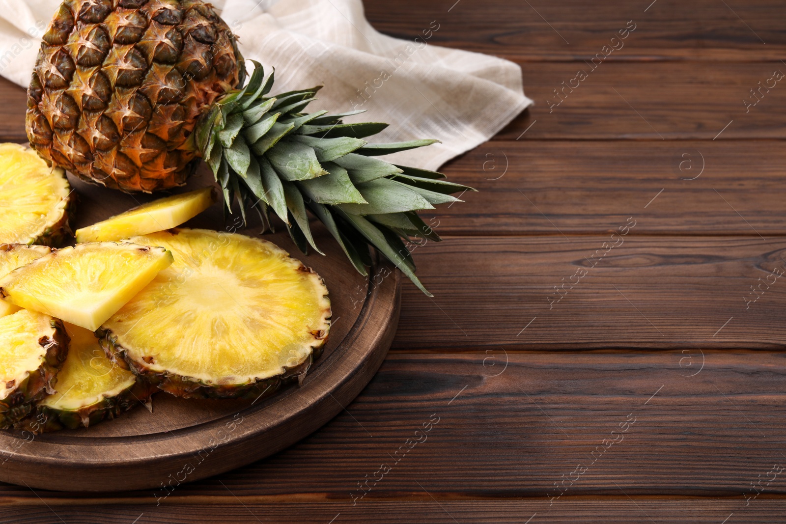 Photo of Pieces of tasty ripe pineapple on wooden table. Space for text