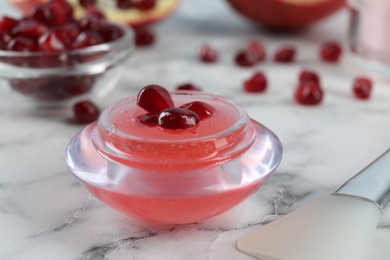 Photo of Cosmetic product made of pomegranate on white marble table, closeup. DIY beauty recipe
