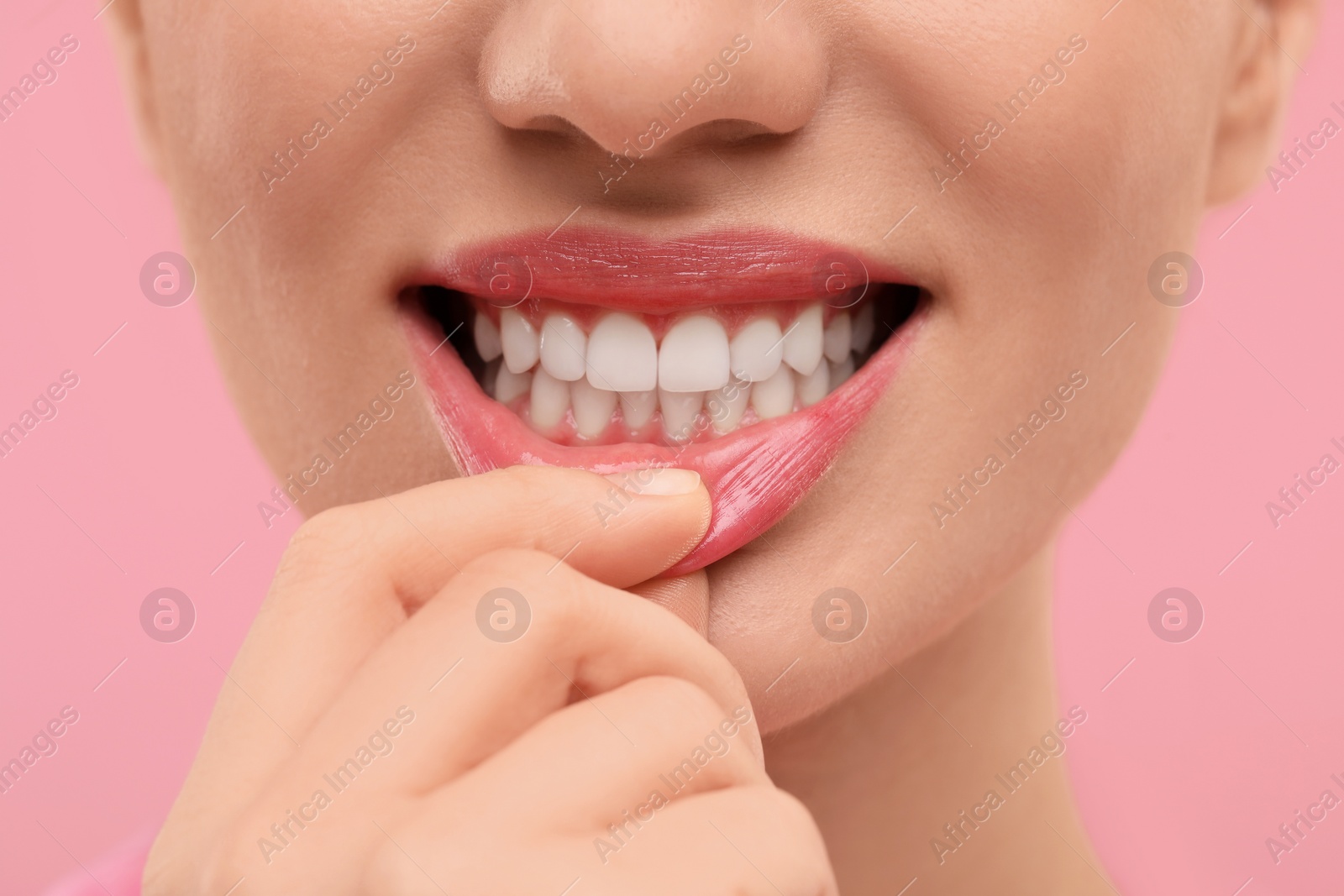 Photo of Beautiful woman showing her clean teeth on pink background, closeup