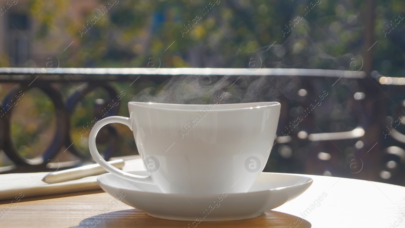 Photo of Cup of aromatic coffee on wooden table outdoors, closeup