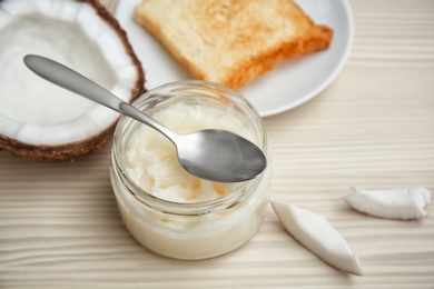 Photo of Jar with coconut oil and fresh toast on wooden background