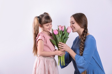 Happy mother and daughter with flower bouquet on white background. International Women's Day