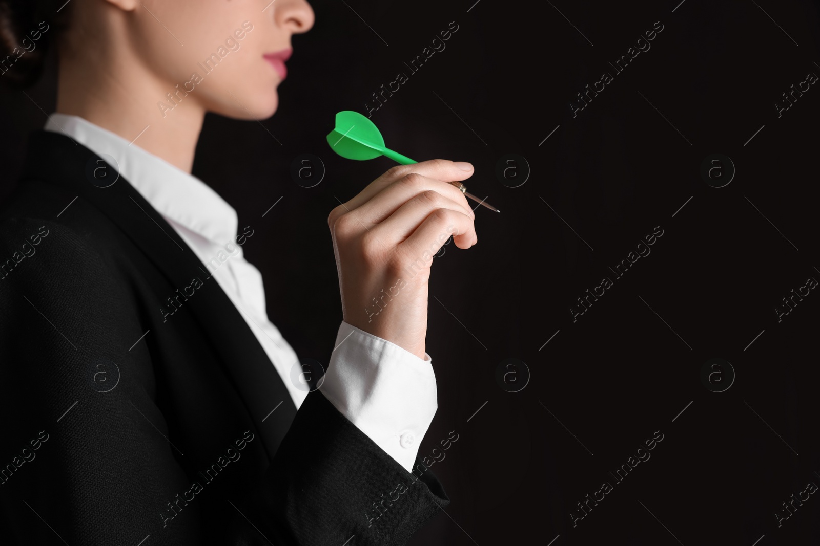 Photo of Businesswoman holding green dart on black background, closeup. Space for text