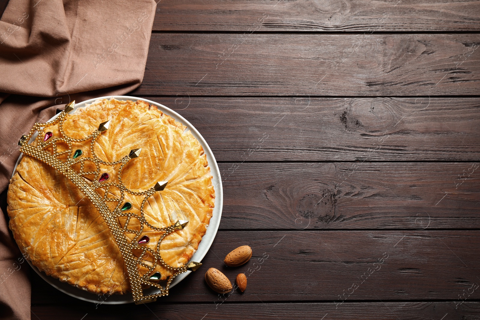 Photo of Traditional galette des rois with decorative crown on wooden table, flat lay. Space for text