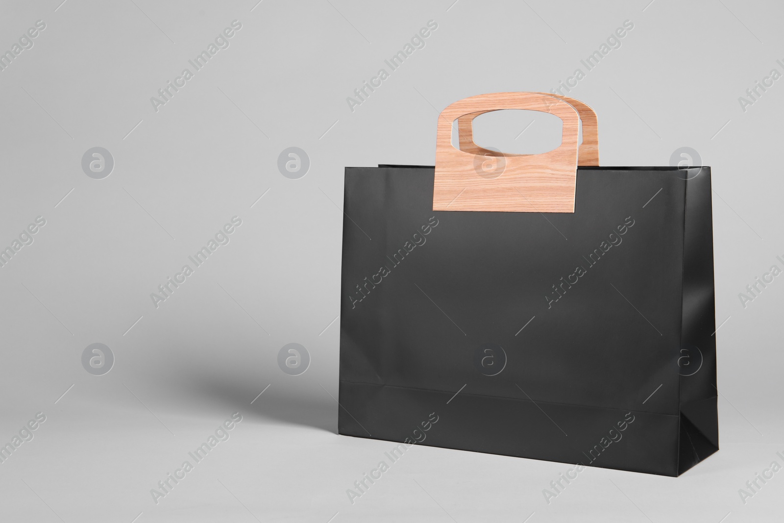Photo of One black paper shopping bag on grey background. Space for text