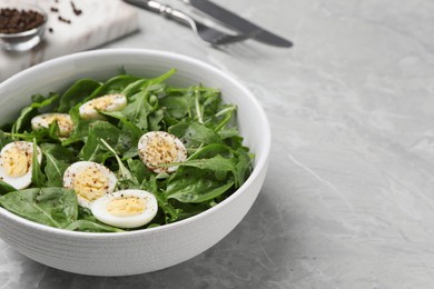 Photo of Delicious salad with boiled eggs and herbs in bowl on light grey marble table, closeup. Space for text