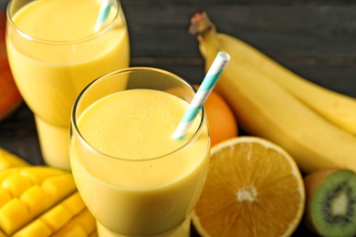 Tasty tropical drink with mango and fresh fruits on table, closeup