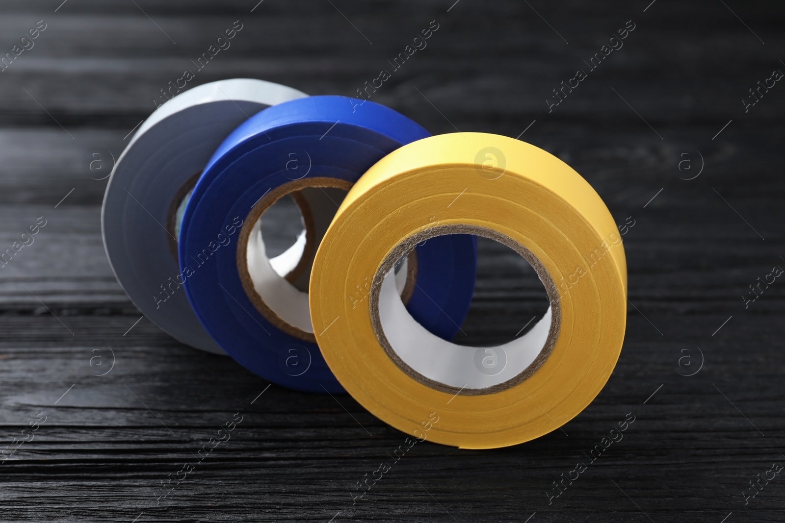 Photo of Colorful insulating tapes on black wooden table