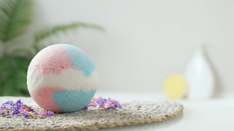 Photo of Beautiful bath bomb on wicker mat indoors, space for text