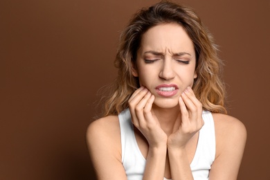 Photo of Young woman suffering from toothache on color background