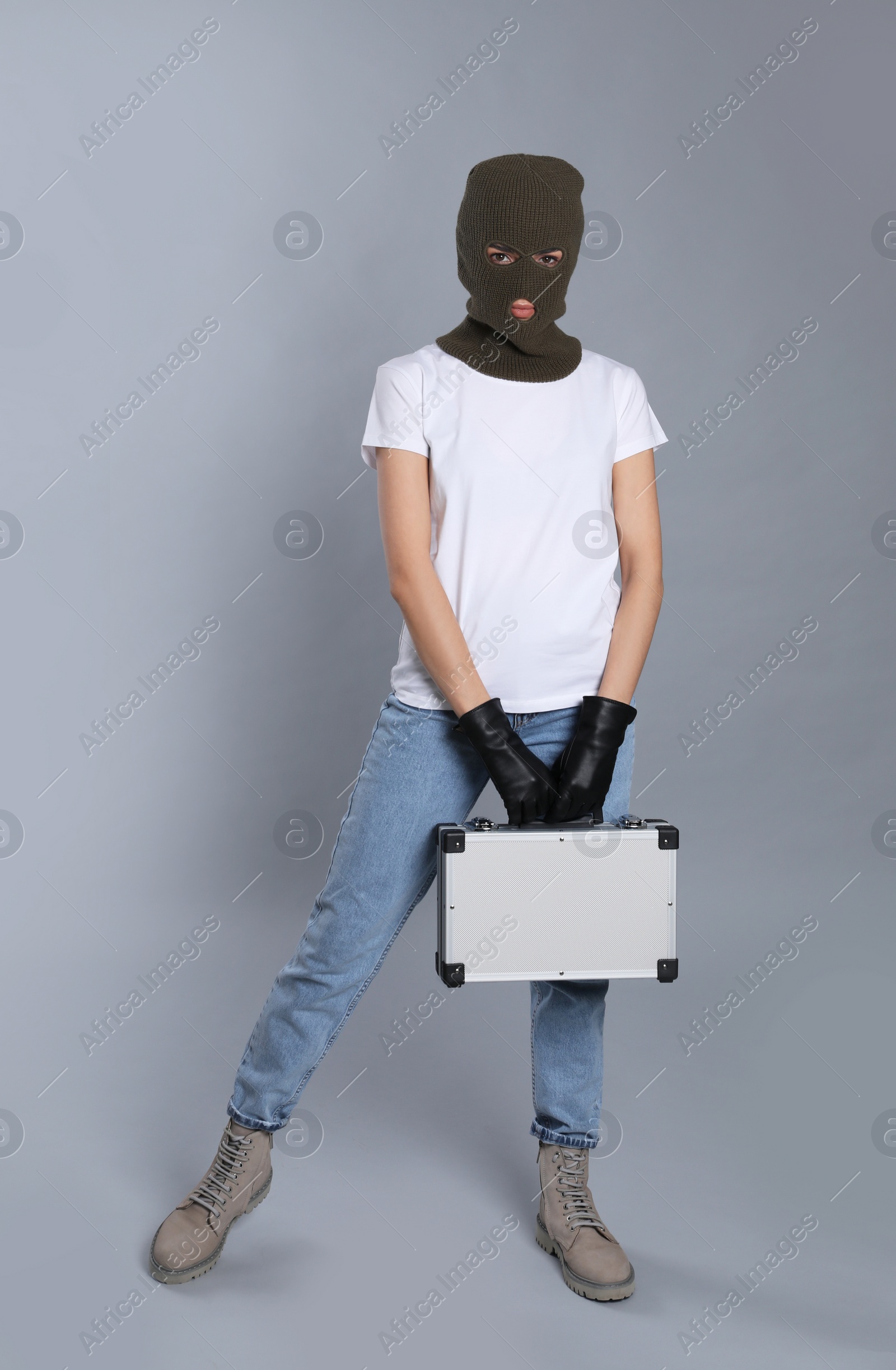Photo of Woman wearing knitted balaclava with metal briefcase on grey background