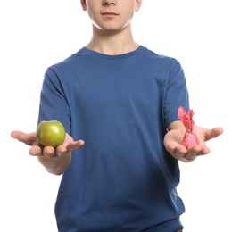 Teen boy with apple and candy on white background, closeup. Diabetes diet