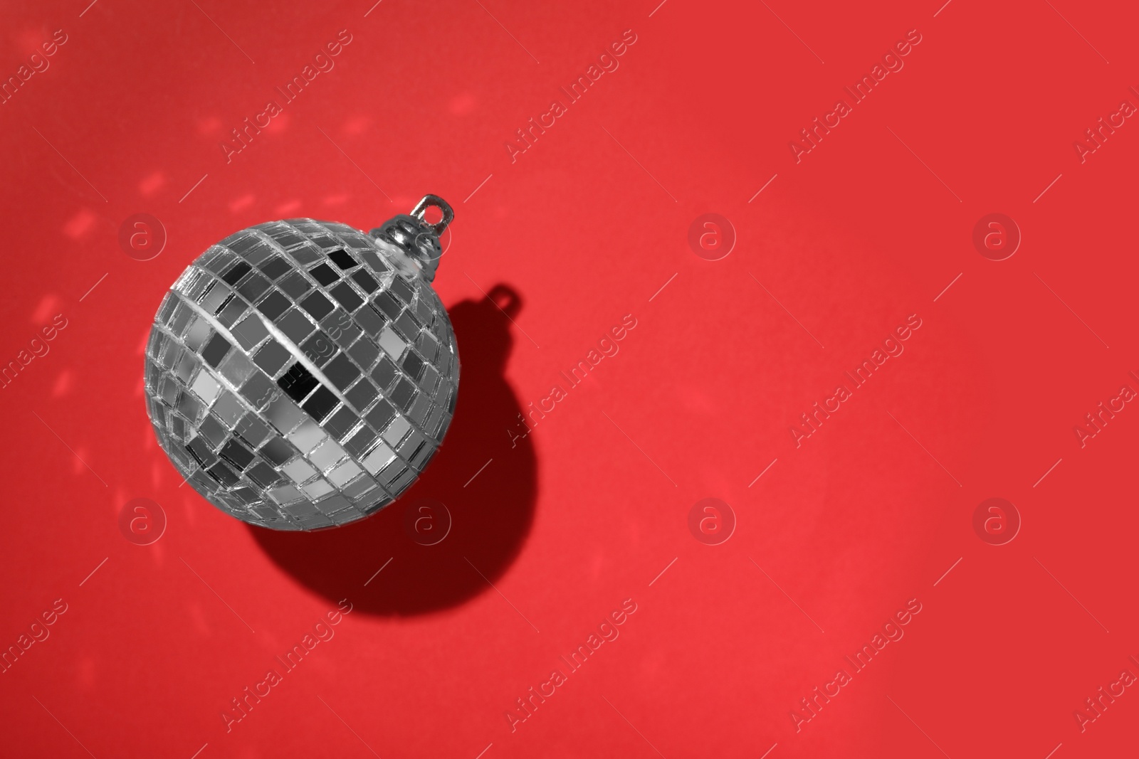 Photo of Bright shiny disco ball on red background, top view. Space for text