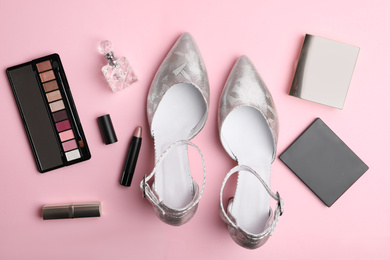 Stylish silver female shoes and decorative cosmetics on pink background, flat lay