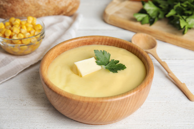 Photo of Delicious corn cream soup served on white wooden table