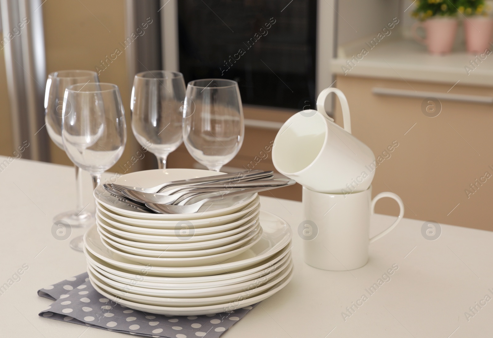 Photo of Clean dishes, glasses, cups and cutlery on table in kitchen