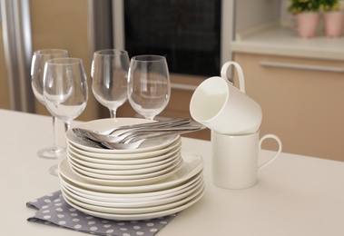 Clean dishes, glasses, cups and cutlery on table in kitchen