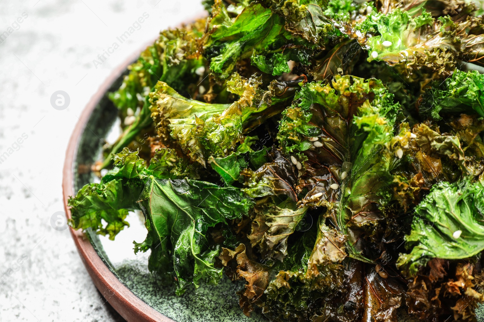 Photo of Tasty fresh kale chips on light table, closeup