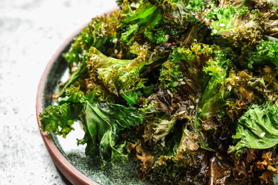 Tasty fresh kale chips on light table, closeup