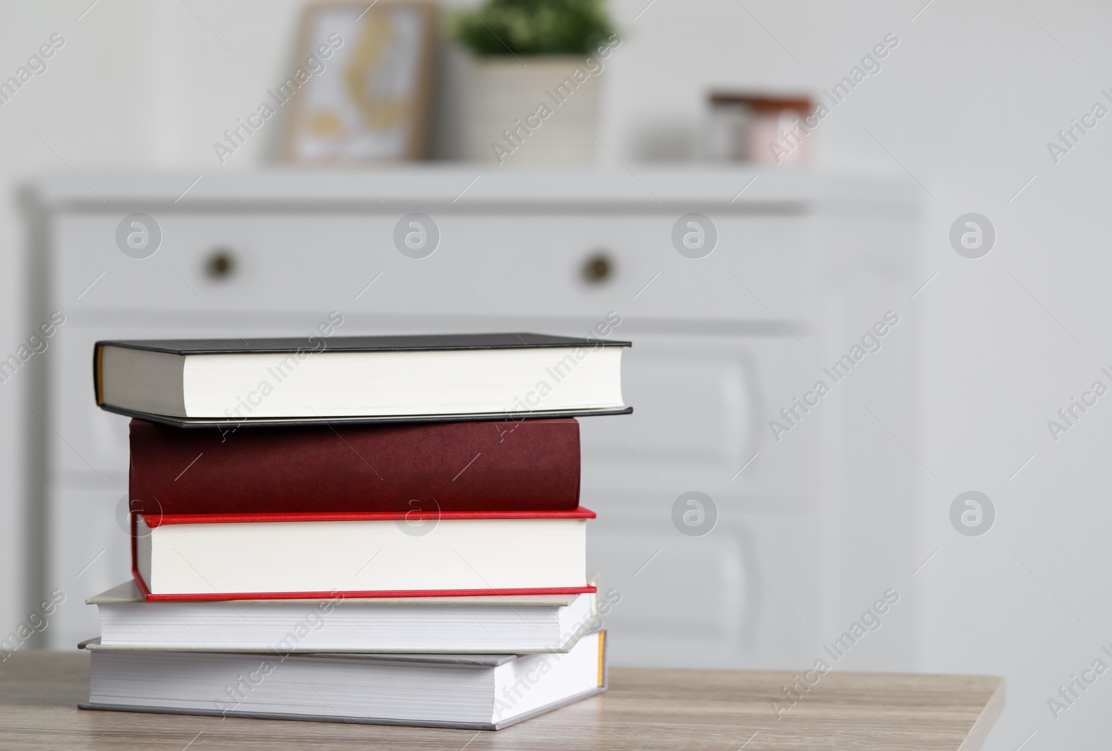 Photo of Stack of hardcover books on wooden table indoors, space for text