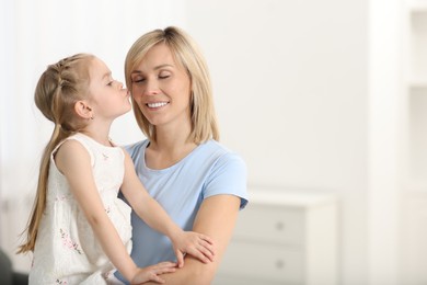 Photo of Daughter kissing her happy mother at home. Space for text