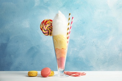 Yummy cotton candy in glass served with sweets on table