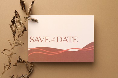 Beautiful card with Save the Date phrase and dry branch on beige background, top view