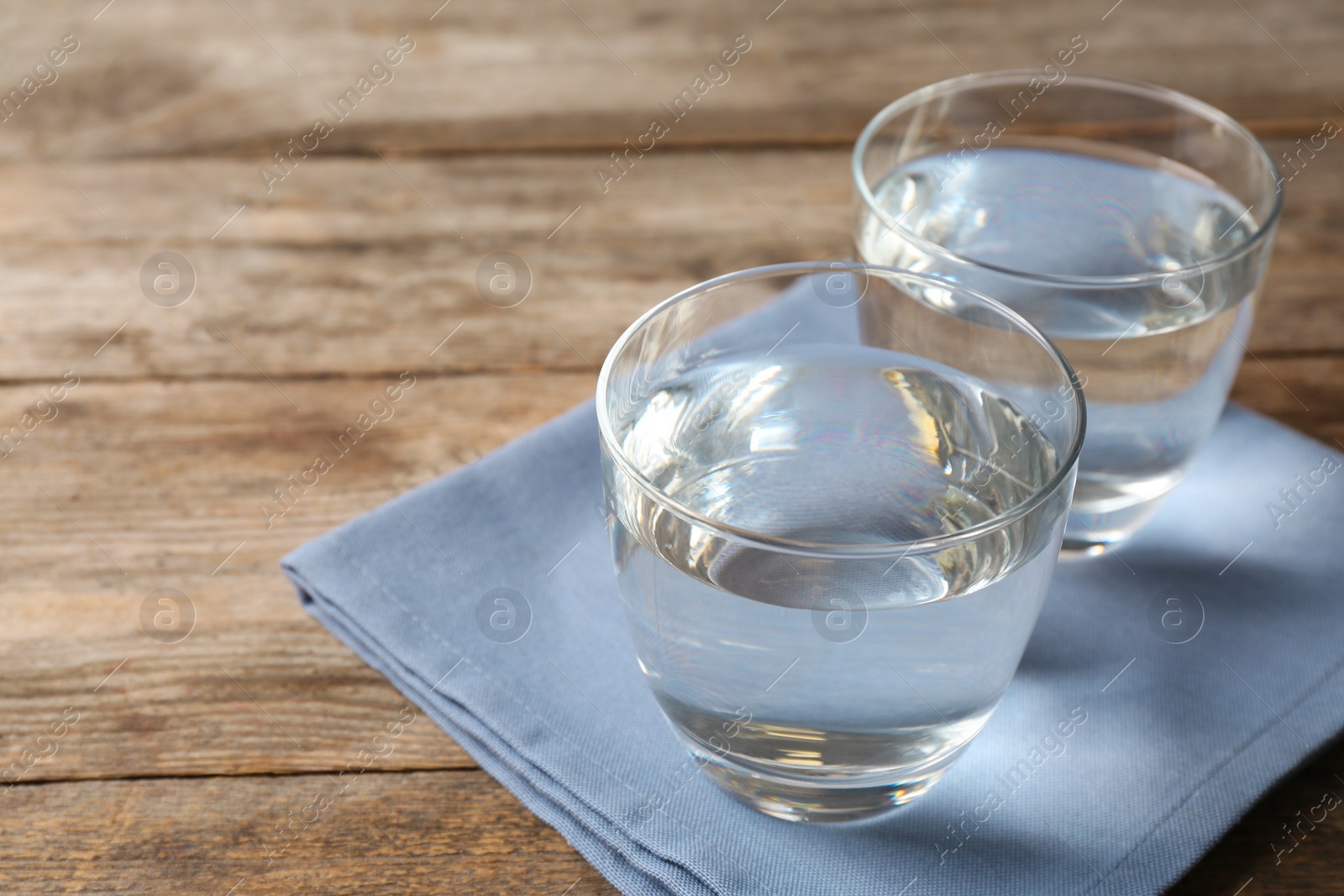 Photo of Glass of water on wooden table. Space for text