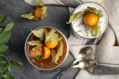Photo of Delicious desserts decorated with physalis on grey table, flat lay