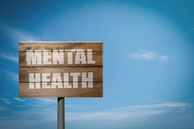 Image of Wooden sign with phrase Mental Health against blue sky on sunny day