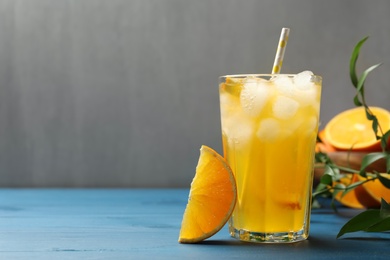 Photo of Delicious orange soda water on blue wooden table. Space for text