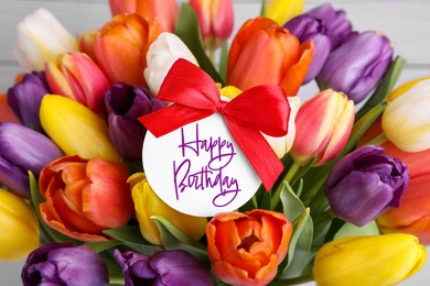 Image of Beautiful bouquet of tulip flowers with Happy Birthday card on light background, closeup