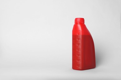 Motor oil in red canister on light background, space for text