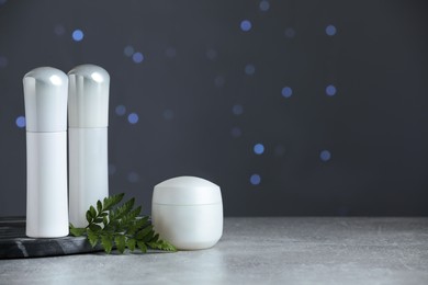 Photo of Skin care products on table against blurred lights, space for text