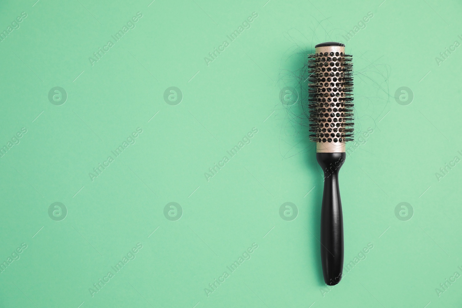 Photo of Professional brush with lost hair on green background, top view. Space for text