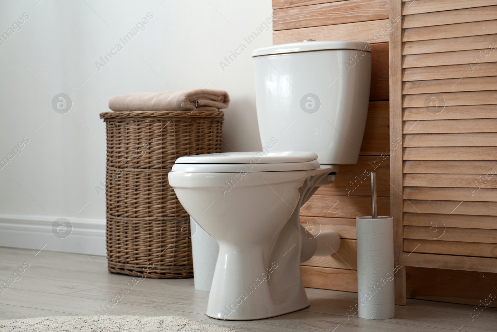 Photo of Toilet bowl near wooden wall in modern bathroom interior