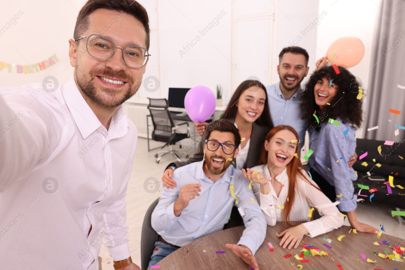 Photo of Coworkers taking selfie during office party indoors