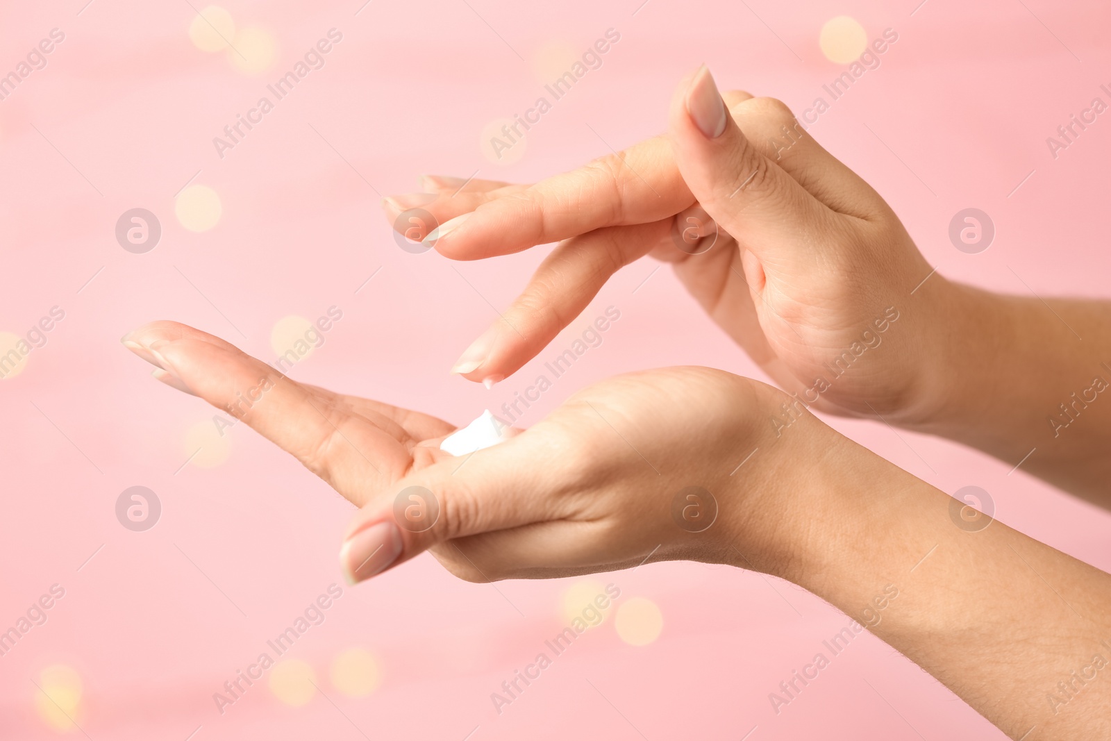 Photo of Woman applying hand cream on blurred background, closeup