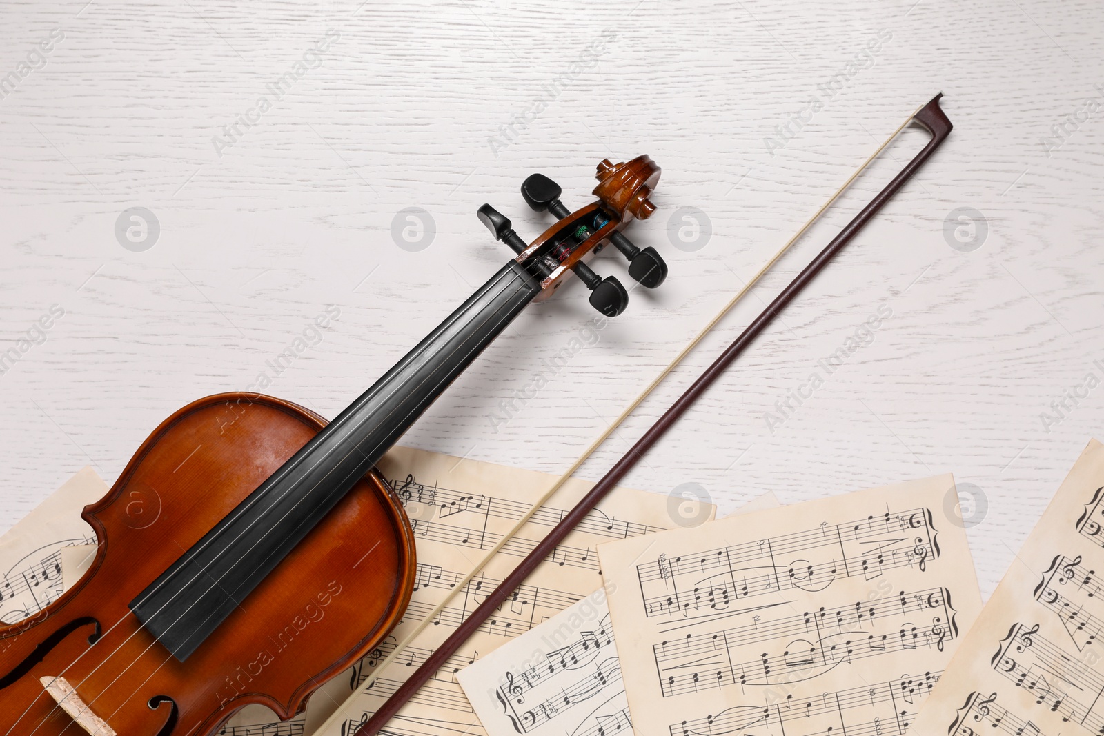 Photo of Violin, bow and music sheets on white wooden table, top view