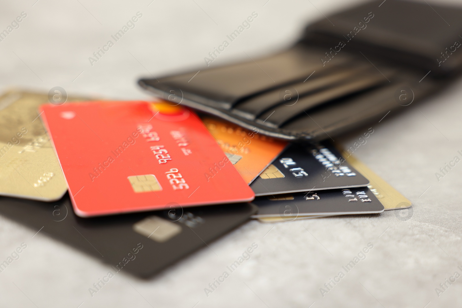 Photo of Many different credit cards and leather wallet on grey table, closeup