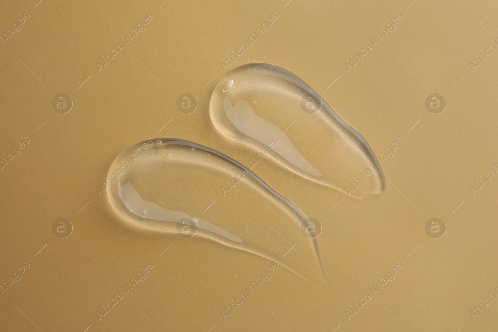 Photo of Sample of transparent gel on dark yellow background, top view