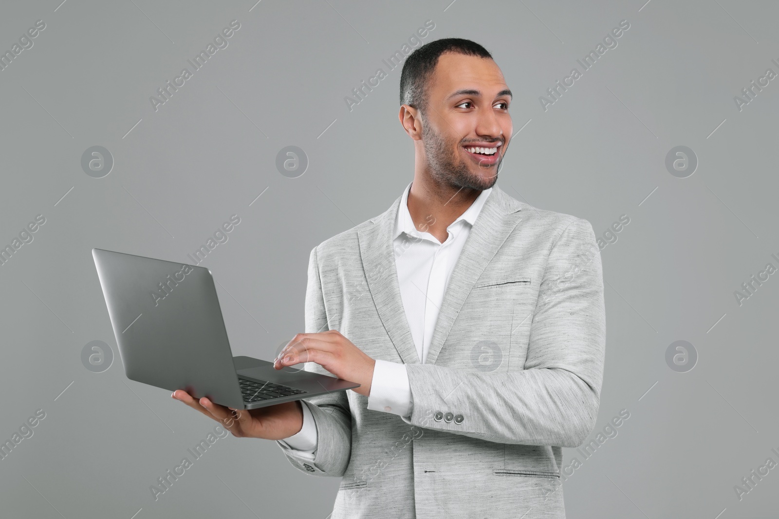 Photo of Young businessman using laptop on grey background