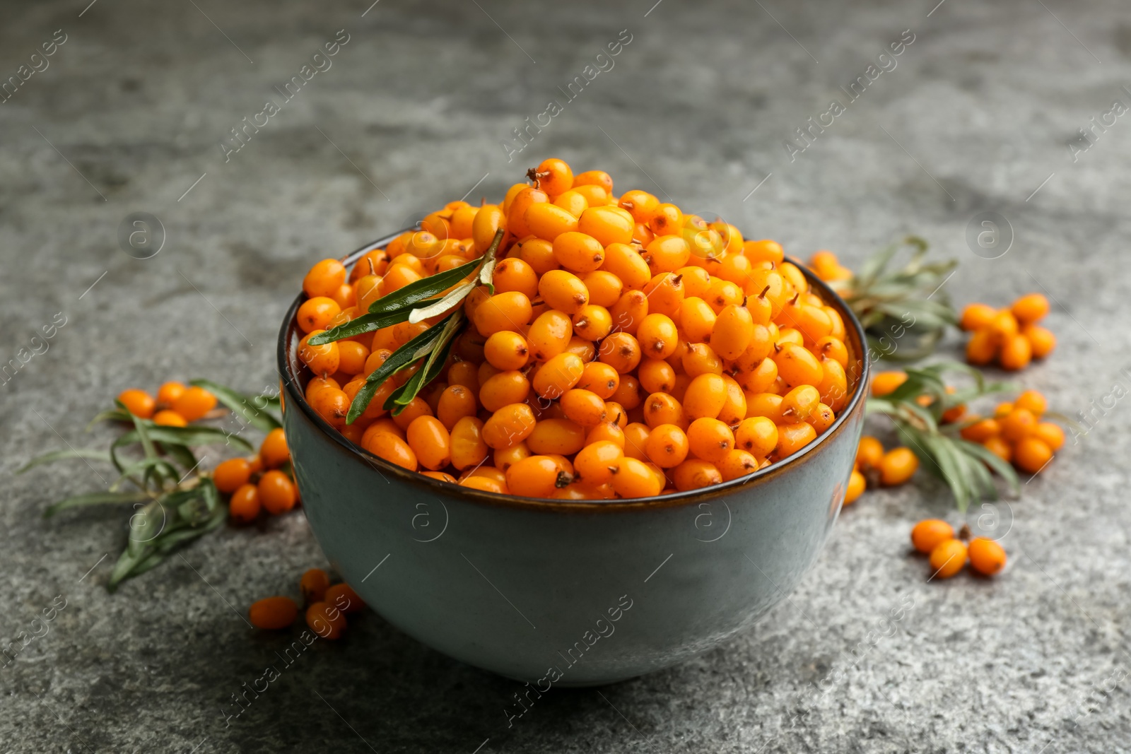 Photo of Fresh ripe sea buckthorn in bowl on grey table