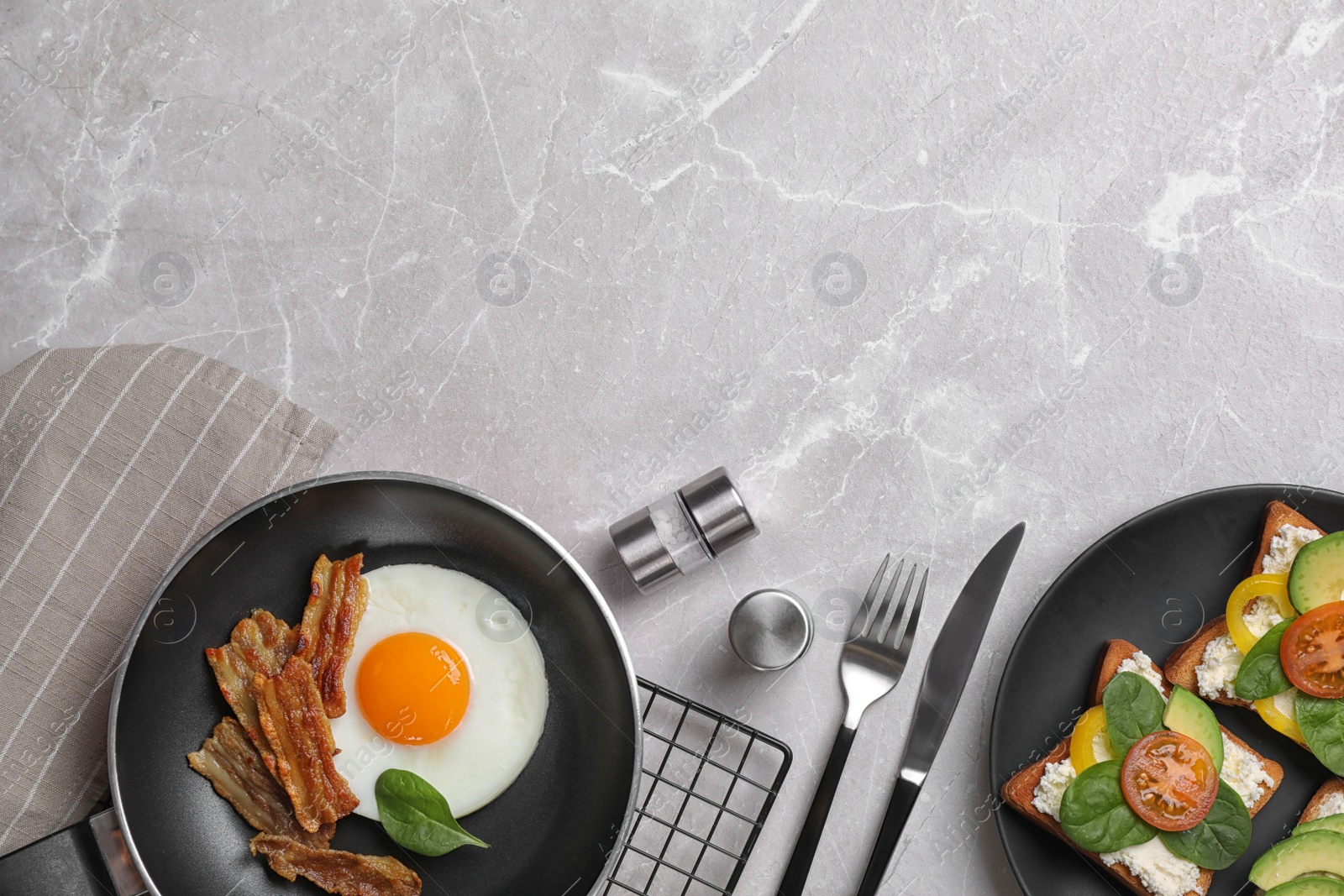 Photo of Tasty breakfast with fried egg, bacon and sandwiches served on light grey marble table, flat lay. Space for text