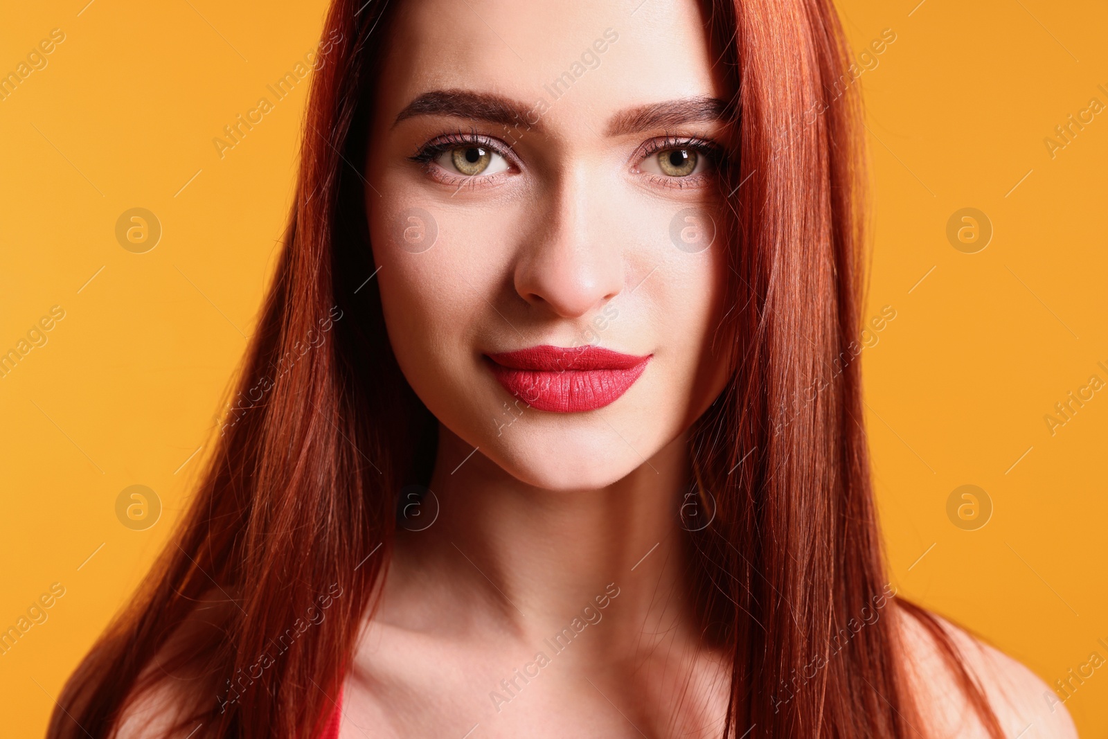 Photo of Beautiful woman with red dyed hair on orange background