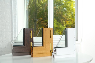 Photo of Samples of modern window profiles on table indoors. Installation service